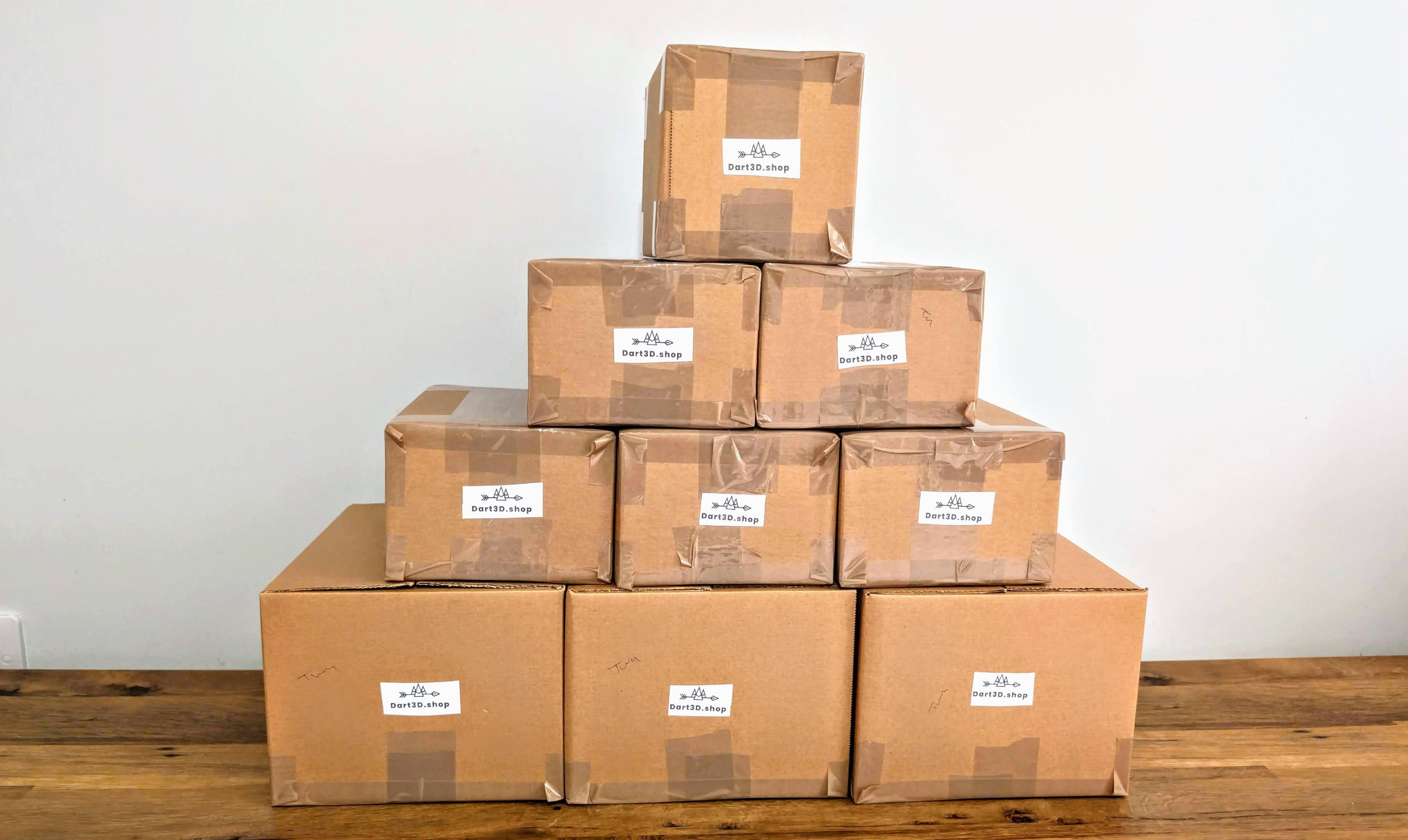 Stack of Dart3D boxes with labels on a wooden surface and white background